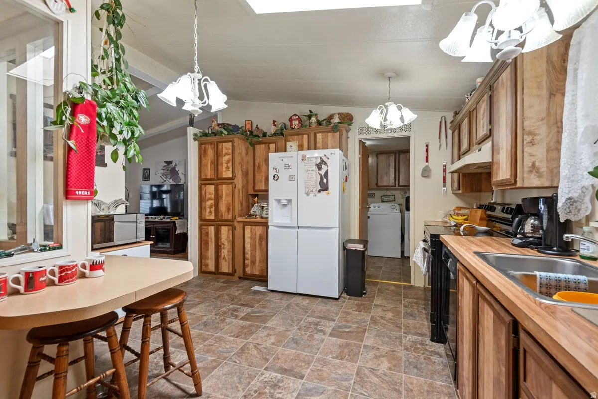 Spacious kitchen featuring extensive wood-finish cabinetry, a double-basin sink, and wood-finish countertops