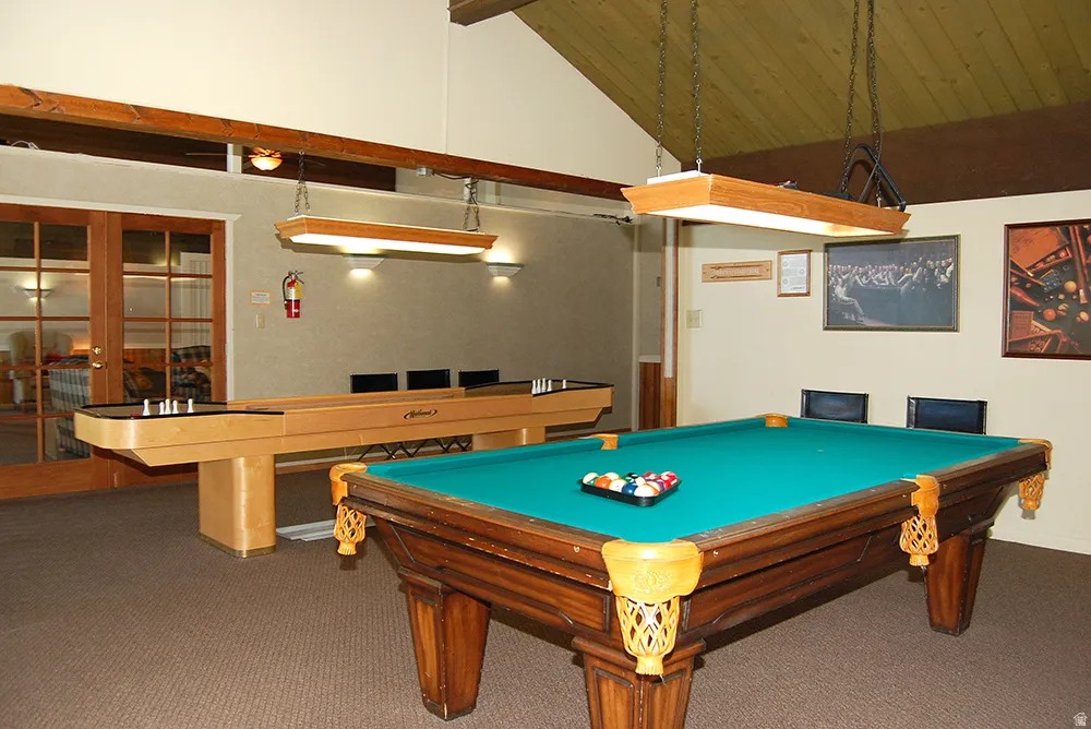Recreation room featuring a vaulted wood-finish ceiling, exposed beams, recessed wall lighting, and a pool table with a dedicated overhead light fixture