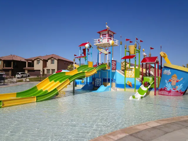 Expansive water park area featuring multiple slides, a water bucket feature, and a central play structure