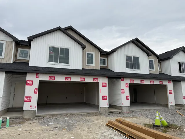 Newly constructed multi-family facade featuring vertical and horizontal siding, dark shingle roofing, and multiple windows