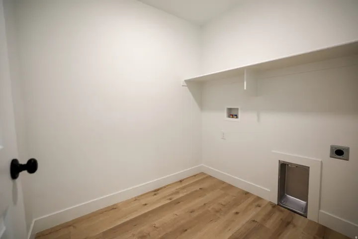 Utility room with wood-finish flooring, white walls, and built-in shelving