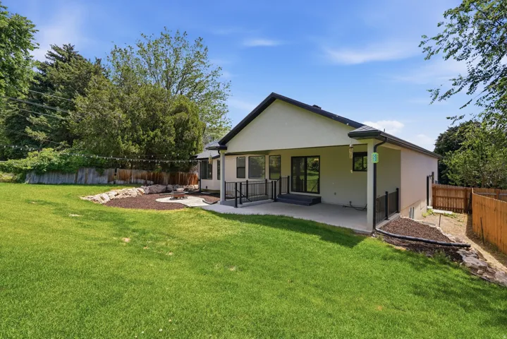 Expansive backyard featuring a manicured lawn, a paved patio, and a dedicated fire pit area