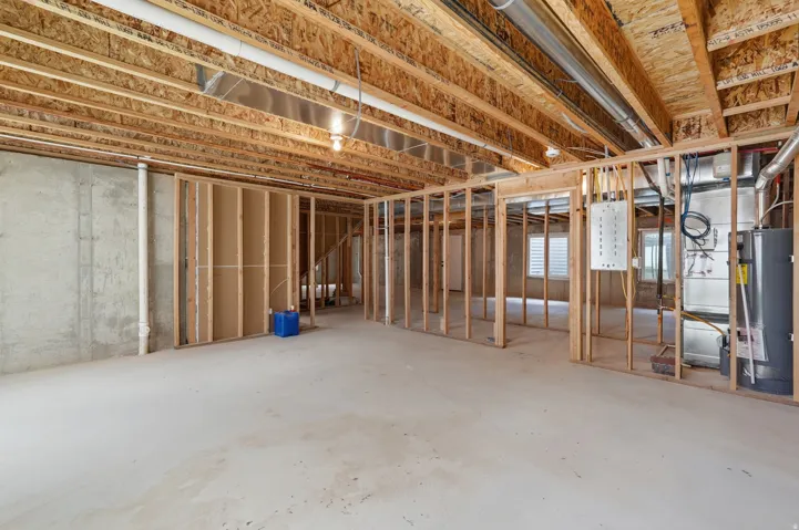 Unfinished basement presenting framed walls, exposed ceiling joists, concrete flooring, and visible utility systems