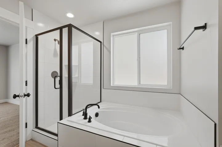 Primary bedroom ensuite bathroom featuring a built-in soaking tub and enclosed shower.