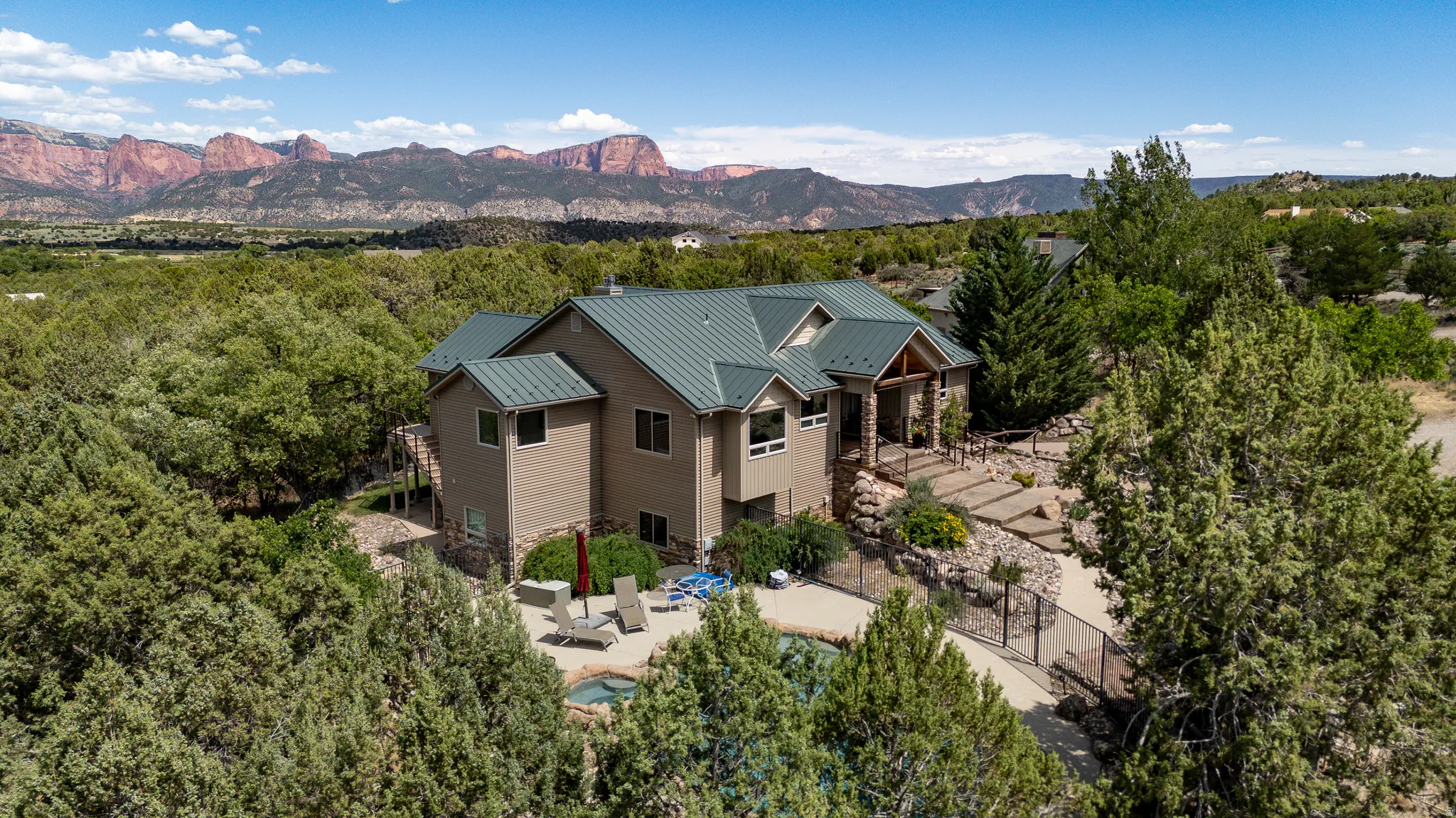 Expansive property featuring a multi-level home with a metal roof, stone accents, and an integrated patio