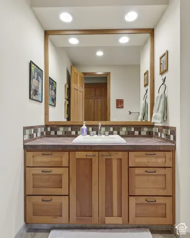 Wood-finish vanity with an integrated sink, mosaic tile backsplash, and a framed mirror