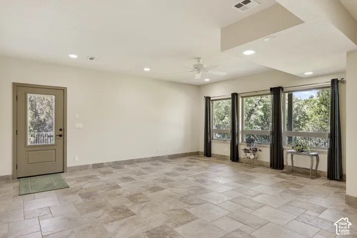 Spacious room featuring neutral-toned tile flooring, recessed lighting, and a ceiling fan
