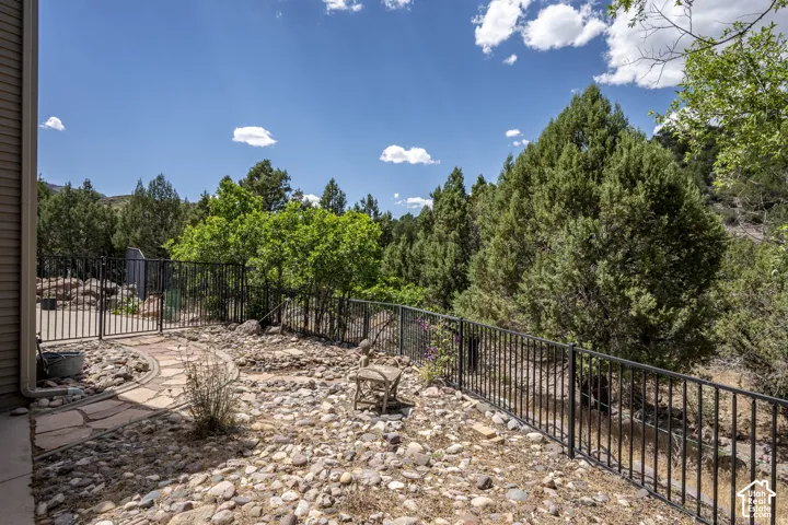 Terraced outdoor space featuring a flagstone path, rock landscaping, and mature trees