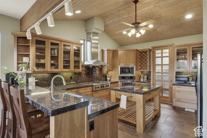 Spacious kitchen featuring wood cabinetry, dark stone countertops, stainless steel appliances, a wood plank vaulted ceiling, and recessed lighting