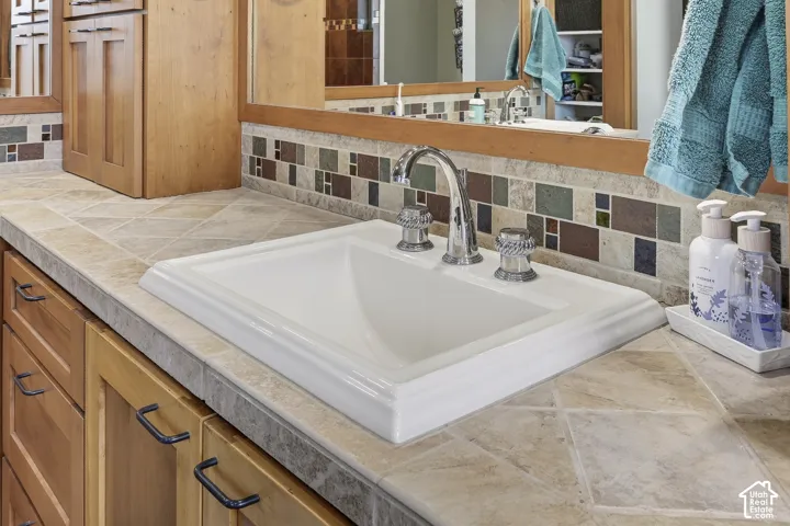 Integrated vanity with a white drop-in sink, chrome faucet, and patterned backsplash
