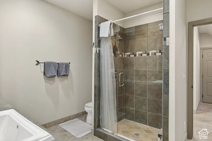 Tiled shower enclosure featuring a mosaic accent band, glass door, and a built-in shower head