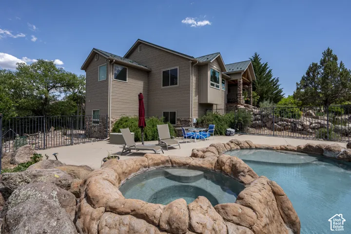 Backyard oasis featuring a rock-edged swimming pool and integrated spa
