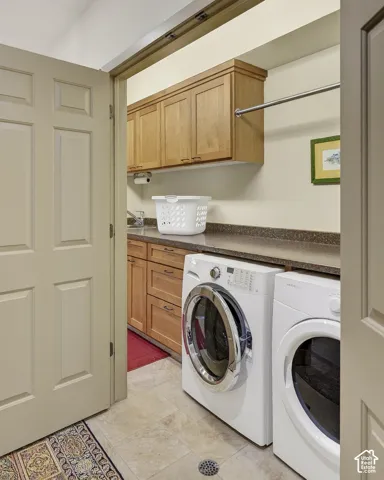 Laundry area featuring wood cabinetry, stone-finish countertops, and tile flooring