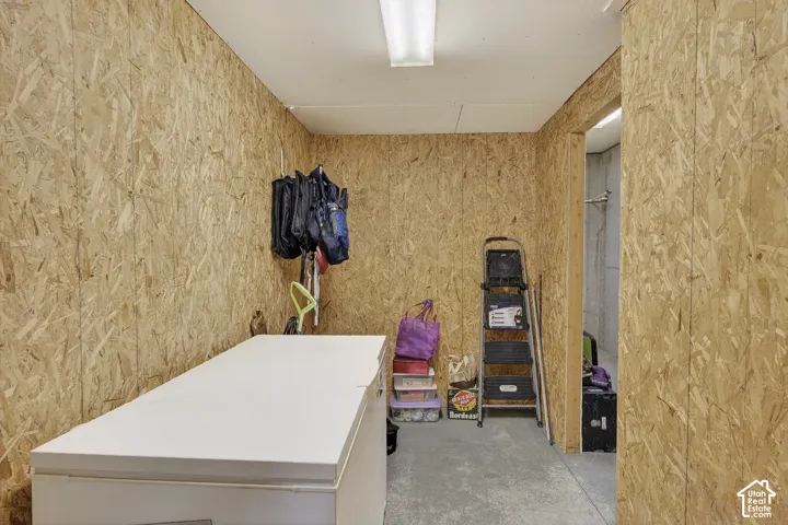 Room featuring oriented strand board walls and concrete flooring