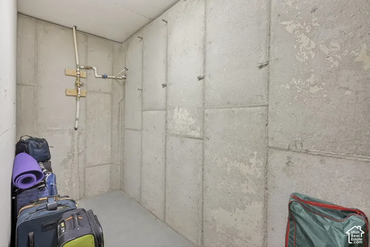 Utility area featuring concrete block walls, exposed plumbing, and a concrete floor