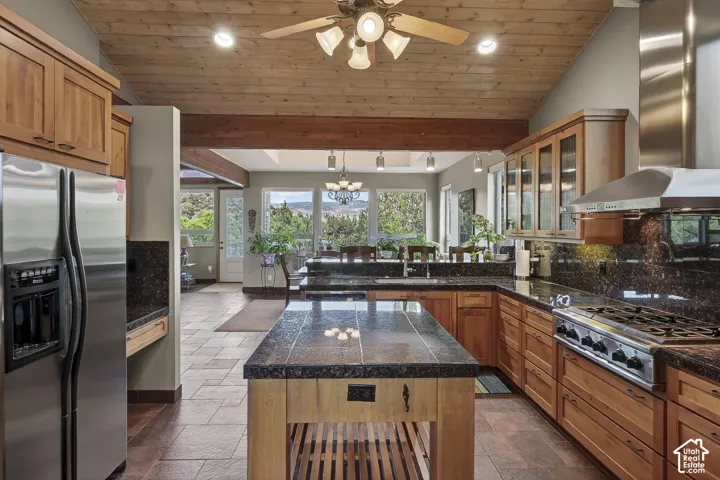 Kitchen featuring wood cabinetry, stainless steel appliances, dark stone countertops, and a wood plank ceiling