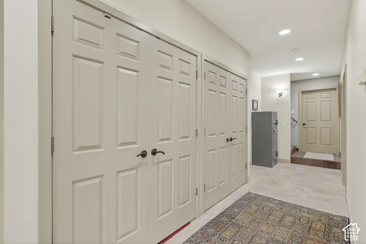Hallway featuring two sets of paneled double doors, recessed lighting, and tile flooring