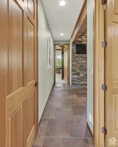 Hallway featuring natural wood panel doors, recessed lighting, and stone flooring