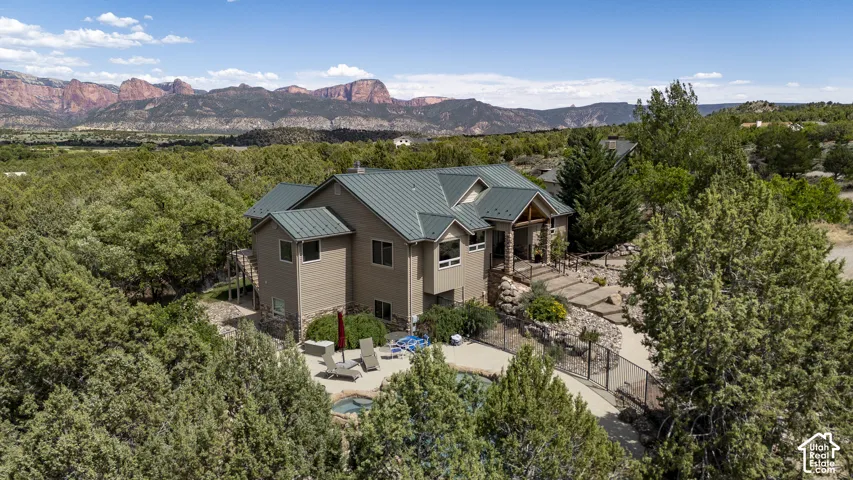 Expansive property featuring a multi-level home with a metal roof, stone accents, and an integrated patio
