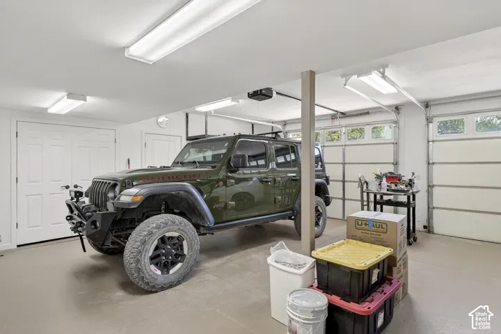 Spacious garage featuring two overhead doors with upper window panels, multiple fluorescent lighting fixtures, and a neutral-toned concrete floor