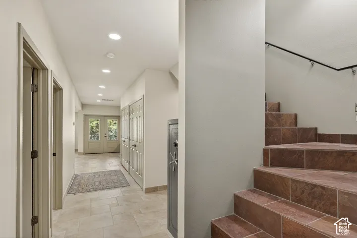 Hallway featuring light-toned tile flooring, recessed lighting, and multiple paneled doors
