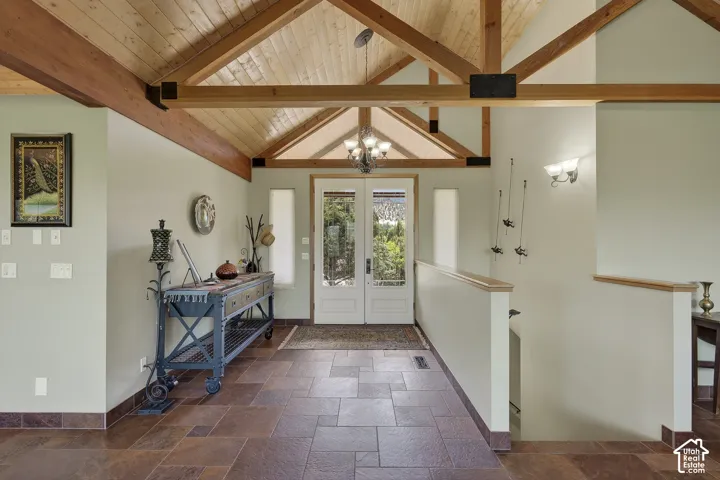 Inviting entryway featuring natural wood vaulted ceilings with exposed beams, tile flooring, and double glass-paneled entry doors
