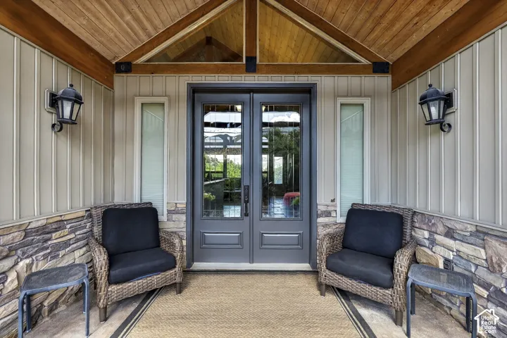 Welcoming front entry featuring a double door with glass inserts, vertical paneling, and an exposed wood ceiling