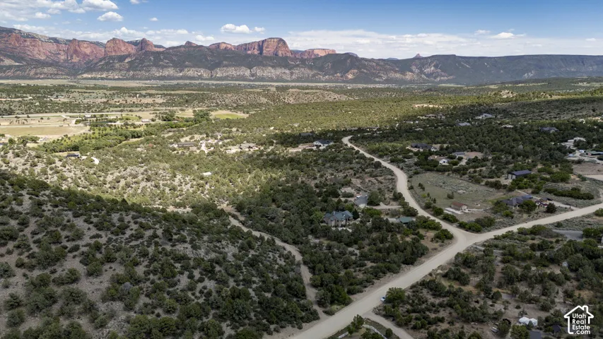 Expansive desert landscape featuring red rock mountain ranges and scattered residential properties
