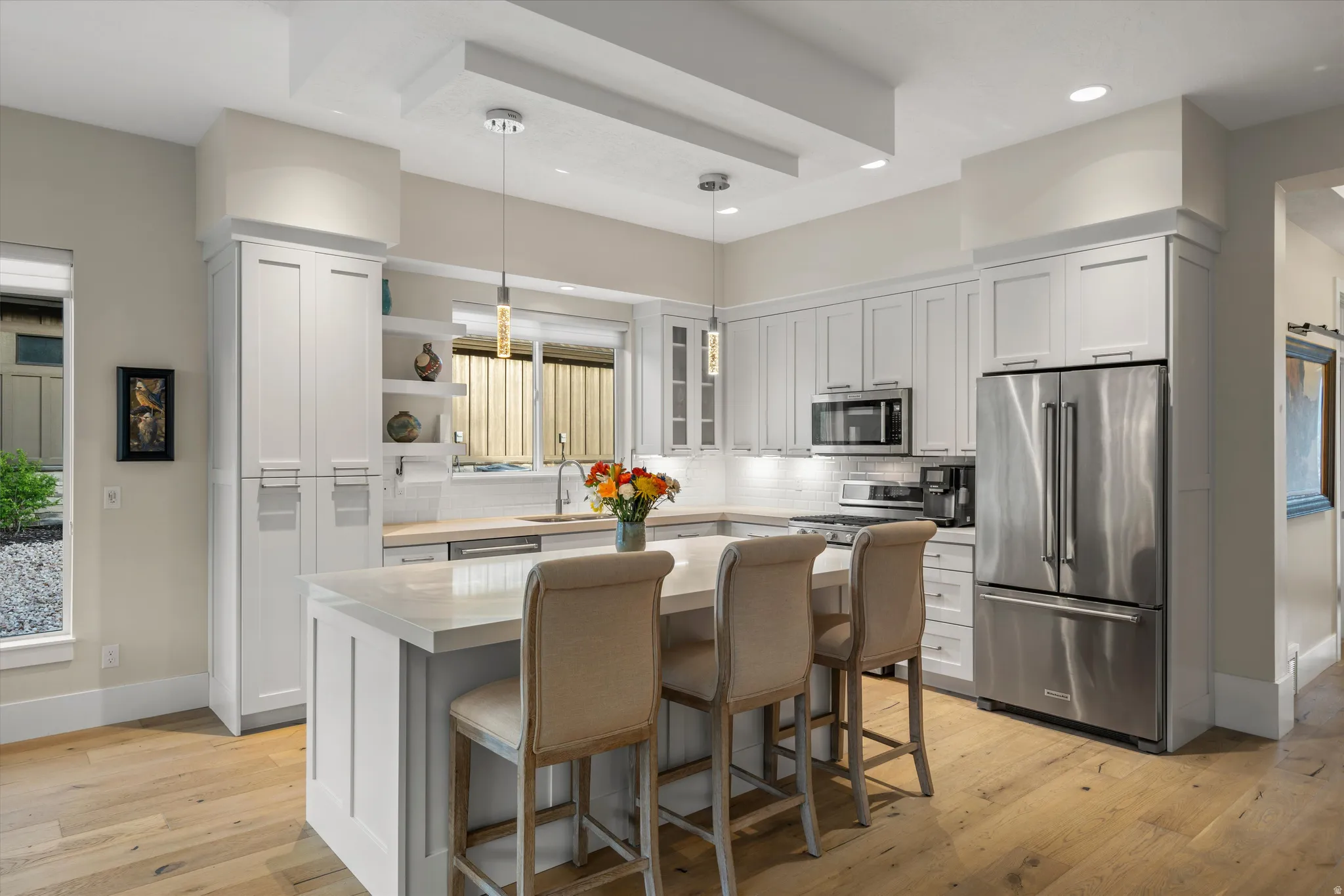 Kitchen featuring light wood-finish flooring, white cabinetry, a central island with countertop seating, stainless steel appliances, and recessed lighting
