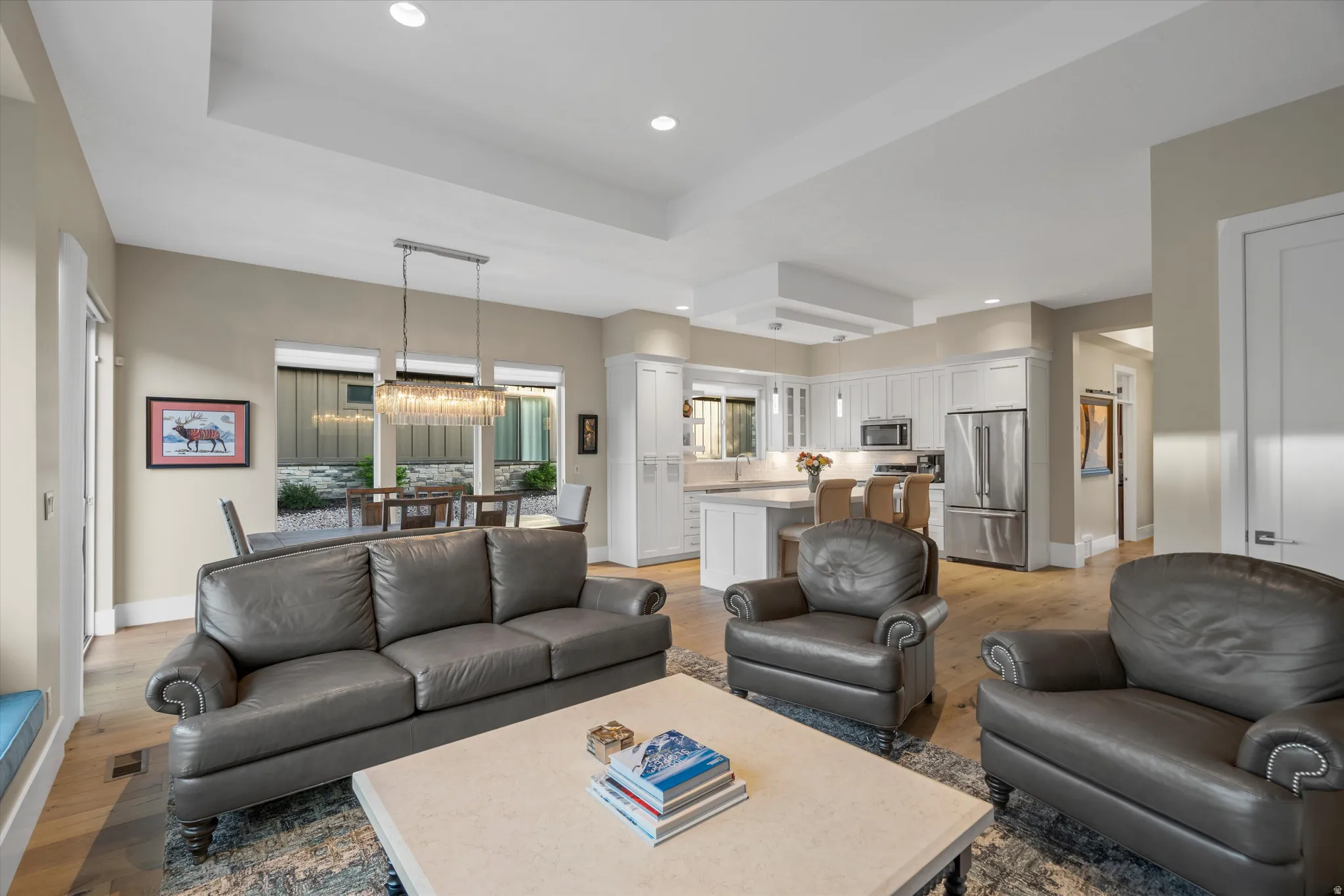 Open-concept living area featuring wood-finish flooring, recessed lighting, and a tray ceiling