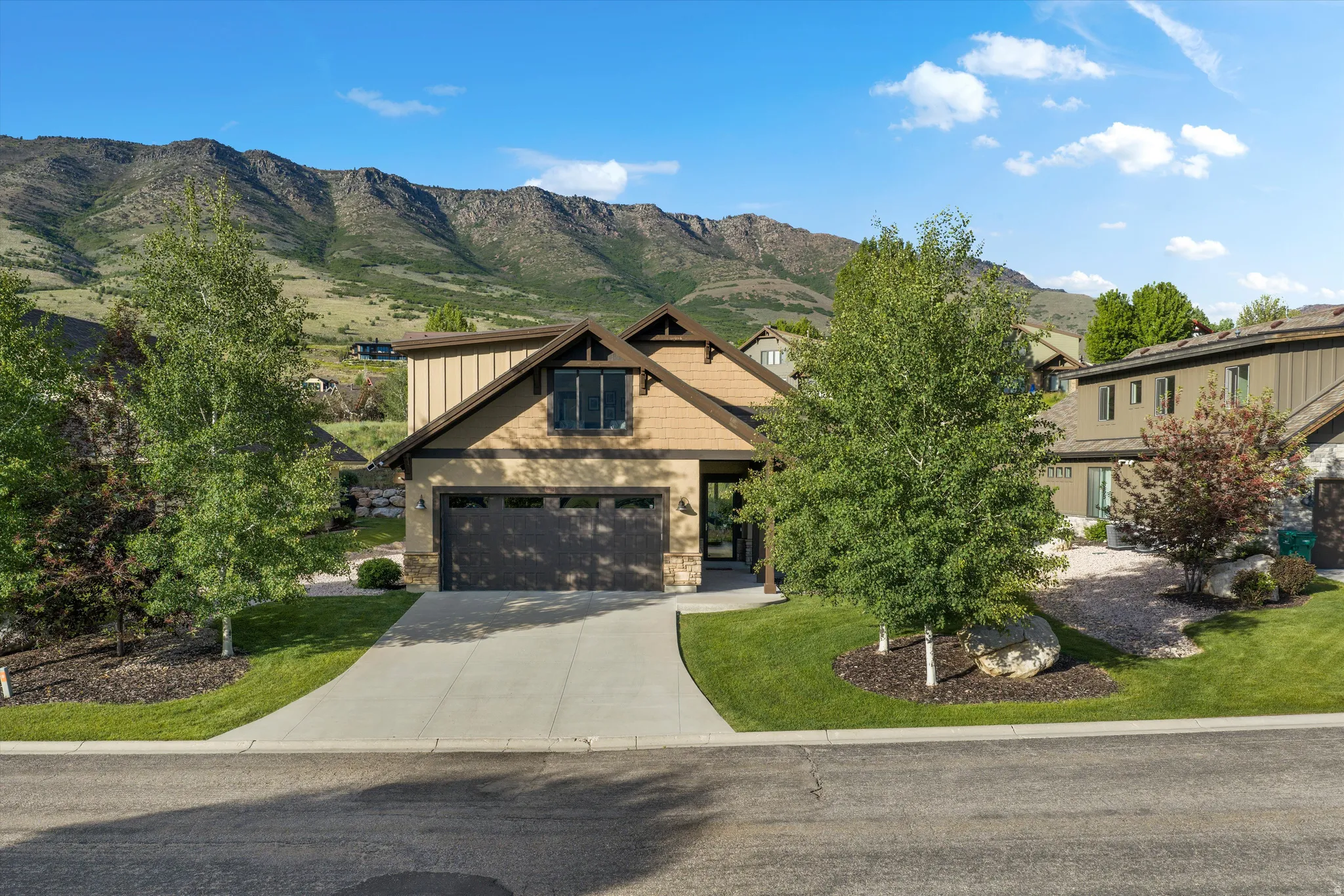 Contemporary property featuring a neutral-toned facade with stone accents and a prominent two-car garage