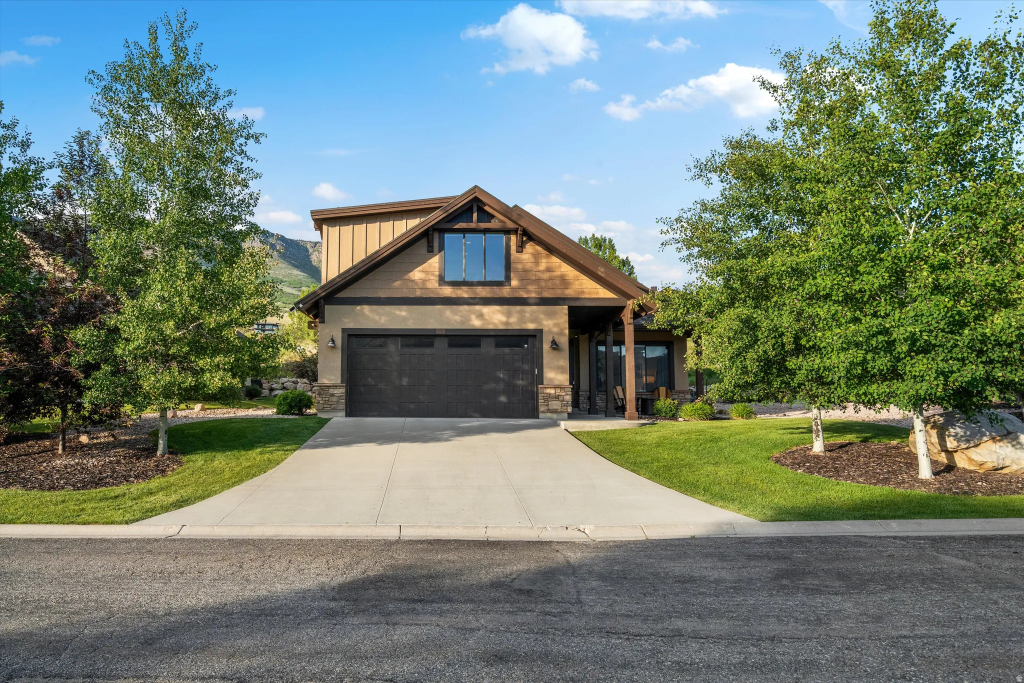 Front facade featuring a two-car garage, covered porch entry, and a prominent gable with board and batten siding