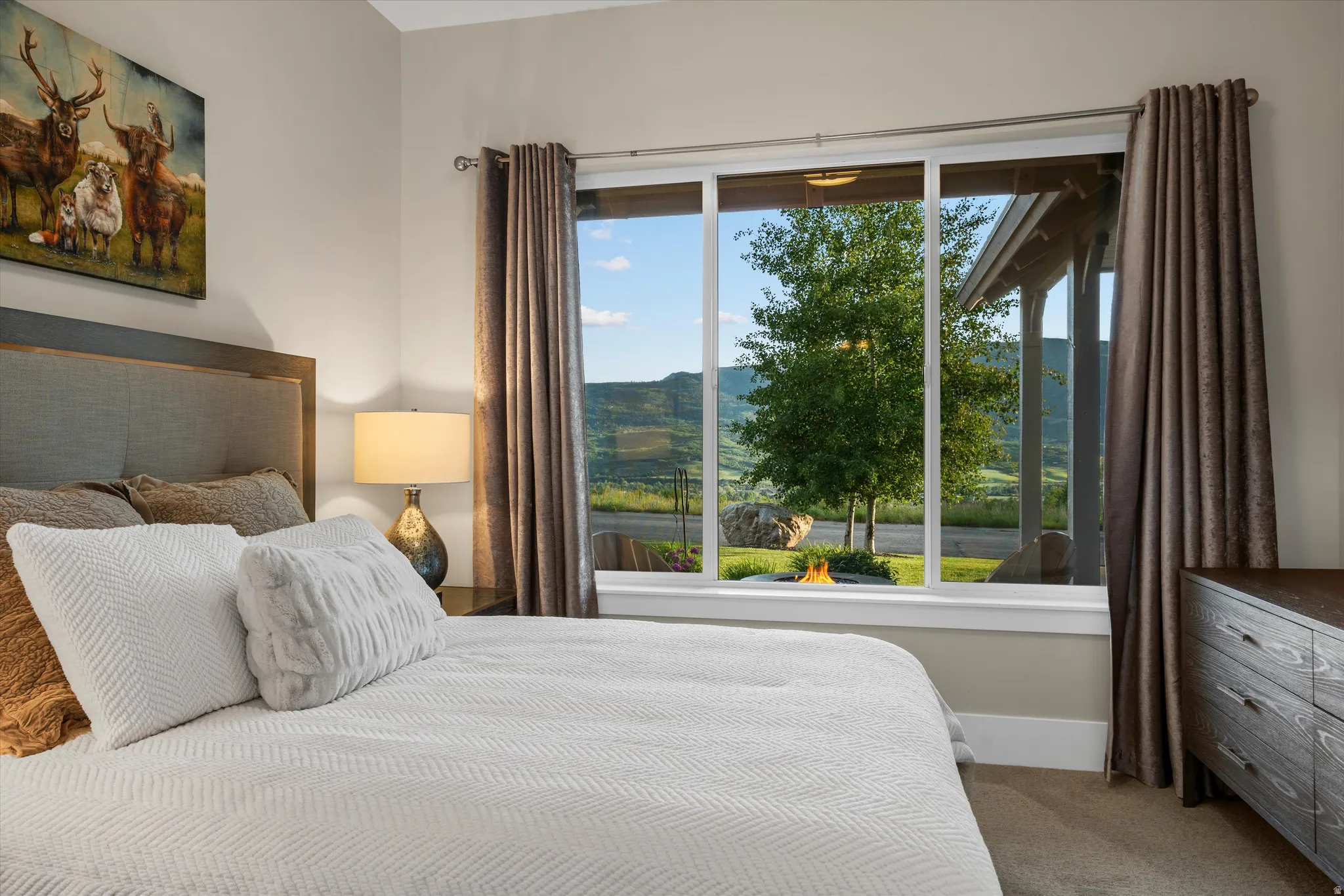 Expansive window featuring a mountain backdrop and outdoor fire pit
