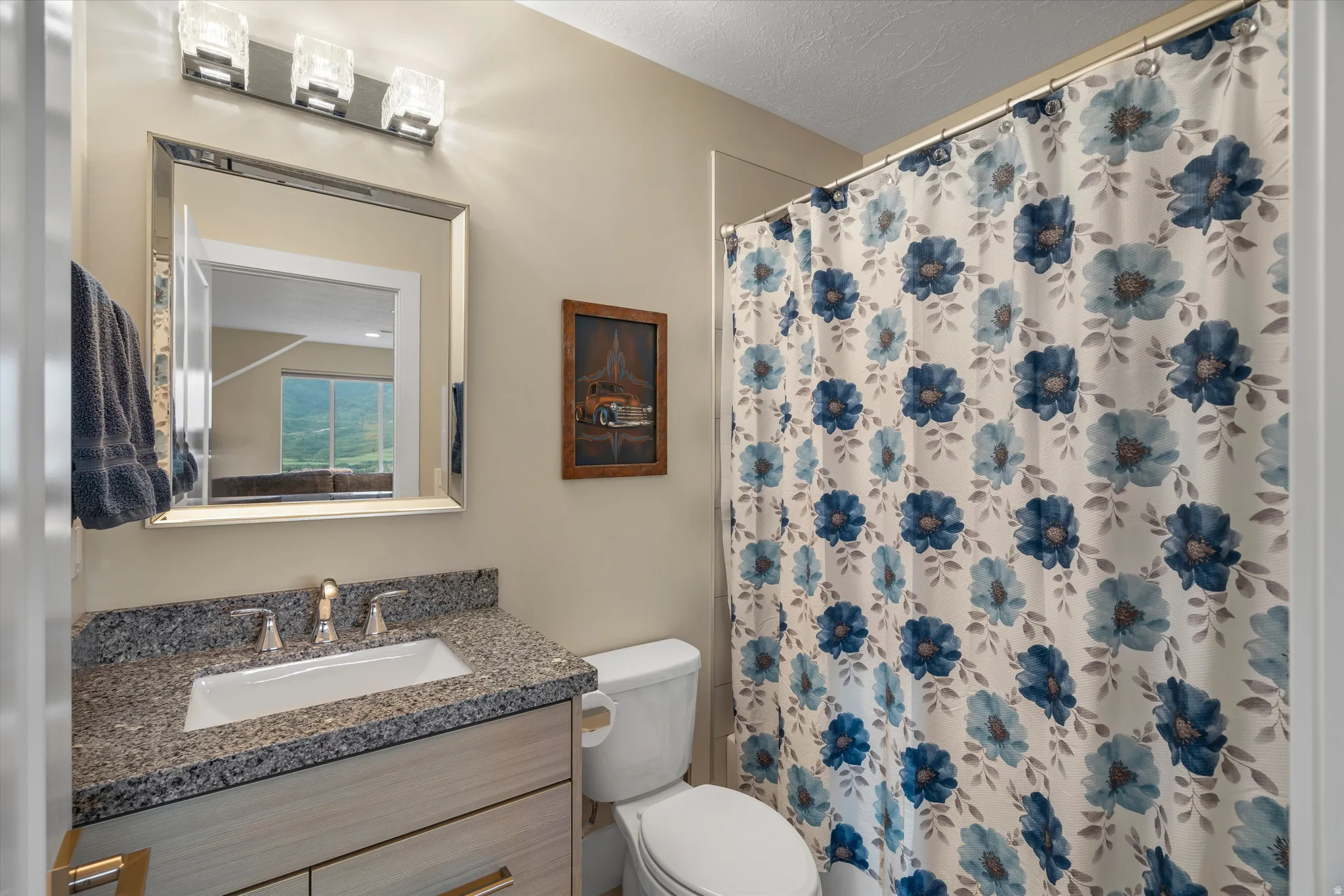 Bathroom featuring a vanity with a light wood-finish cabinet, speckled countertop, and rectangular undermount sink