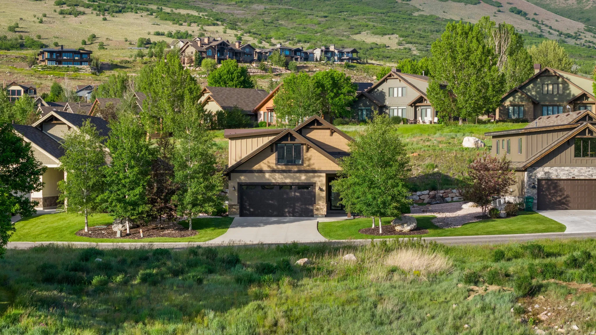 Craftsman-style residence with a two-car garage, stone and siding exterior, and a paved driveway