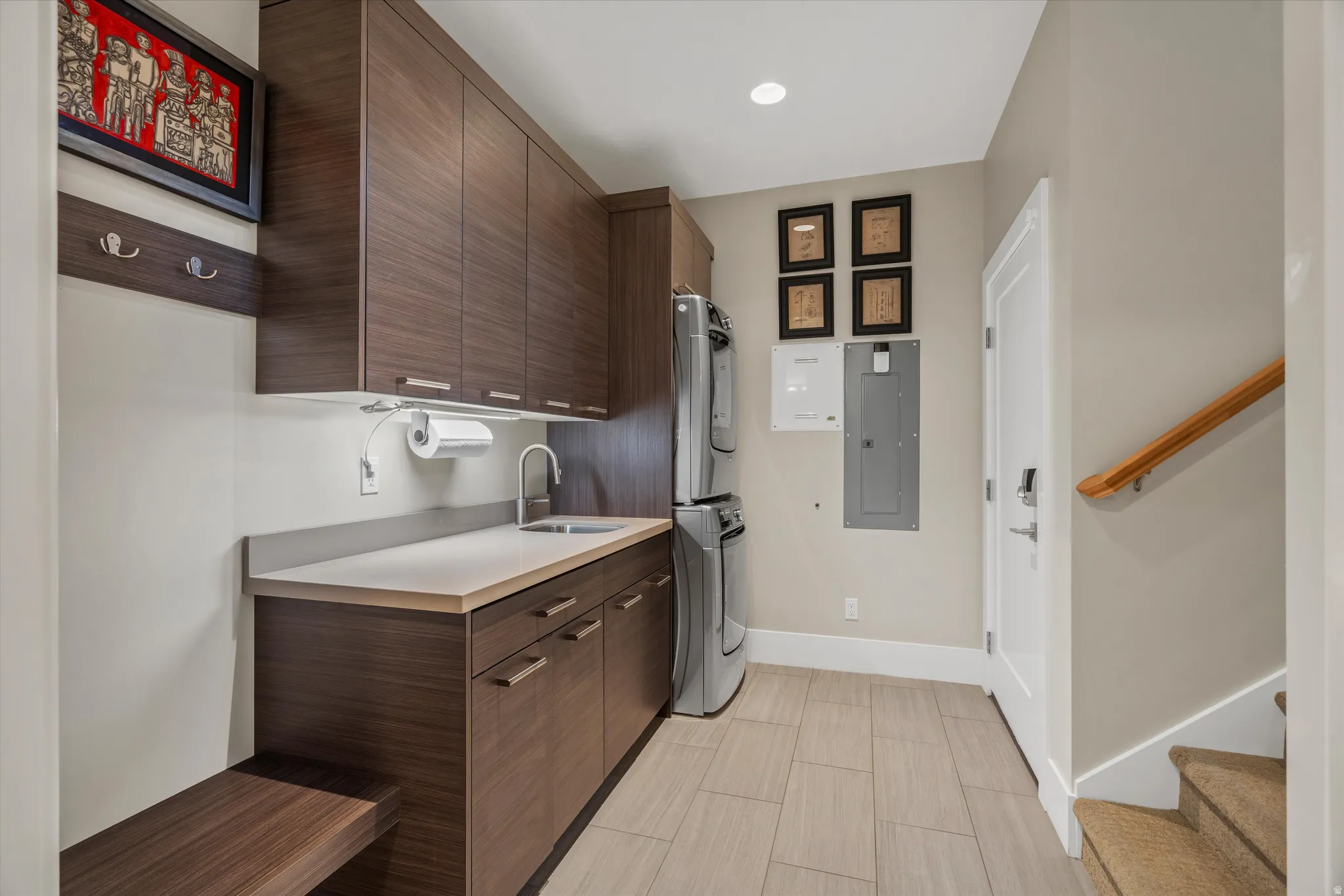 Utility area featuring wood-finish cabinetry, light-toned countertop with integrated sink, and tile flooring
