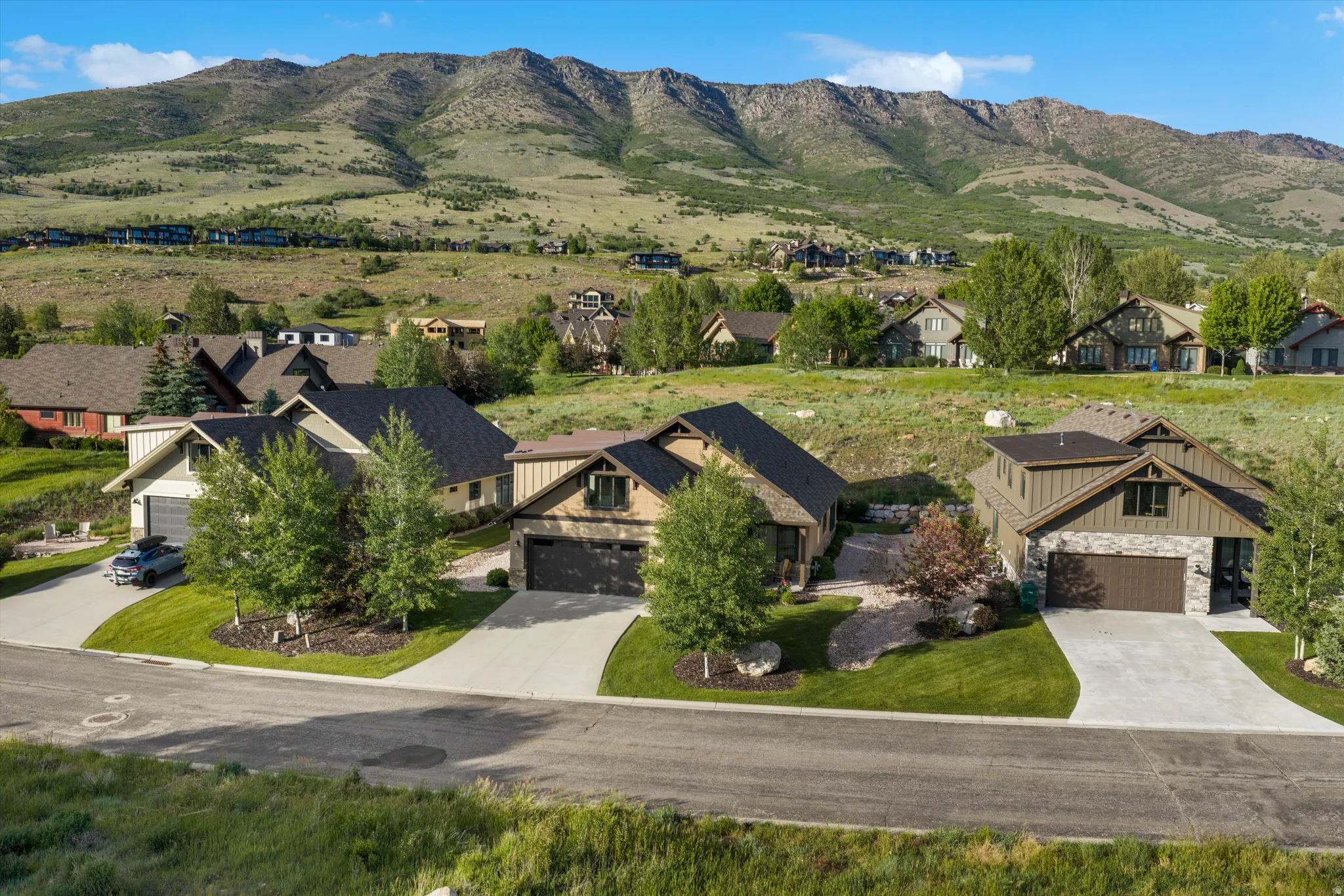 Modern mountain-style residence featuring a stone and wood-look facade, an attached garage, and a concrete driveway
