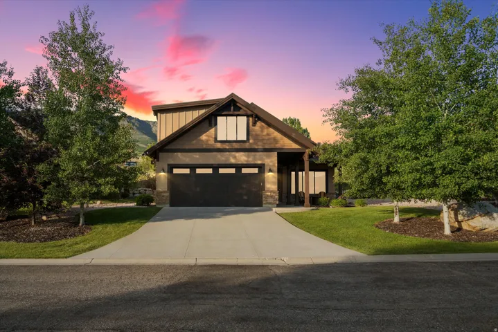 Craftsman-style exterior featuring a dark brown garage door, stone accents, wood siding, and gabled roofing