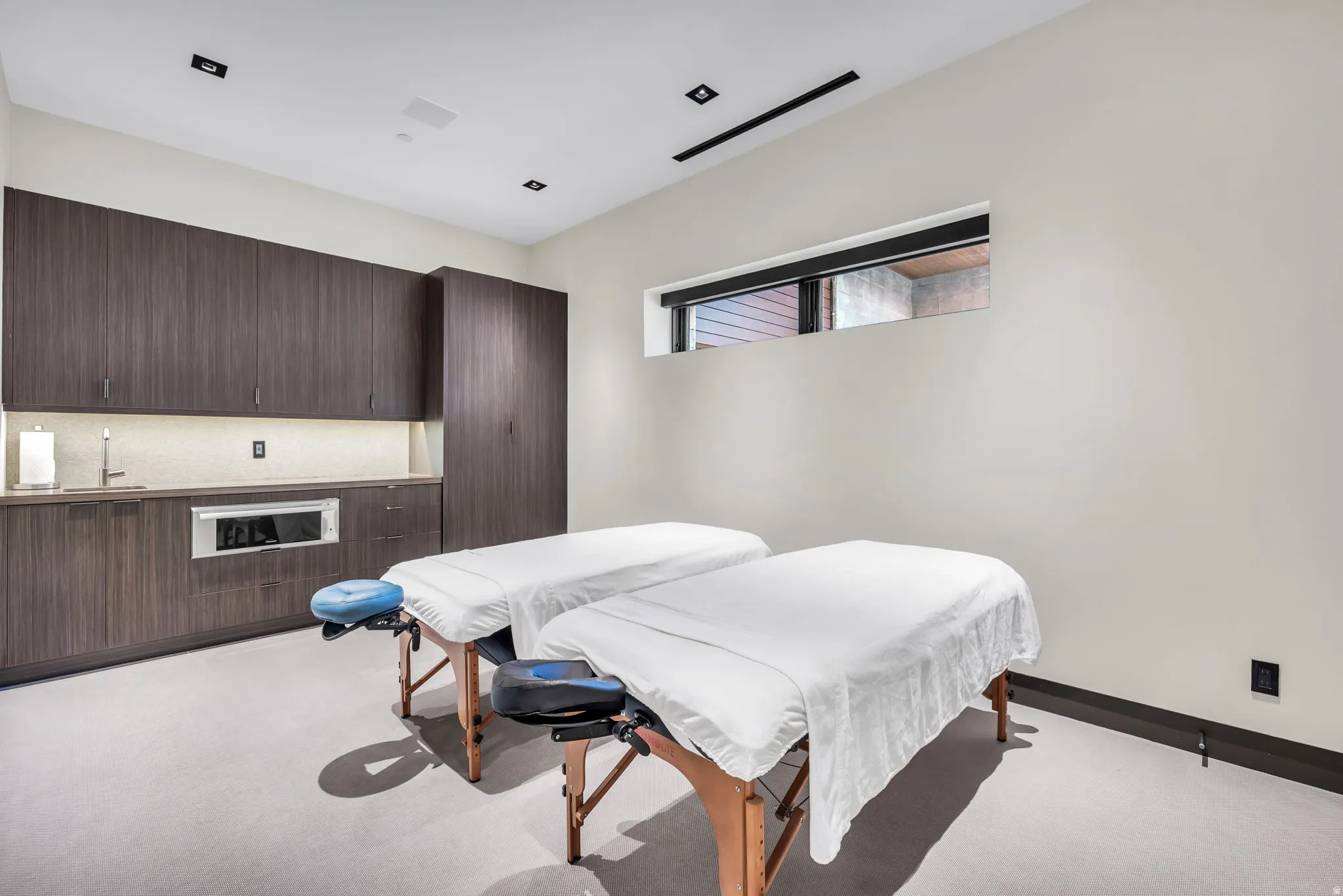 Spacious room featuring dark wood-finish cabinetry, a built-in stainless steel microwave, and a wet bar with an undermount sink
