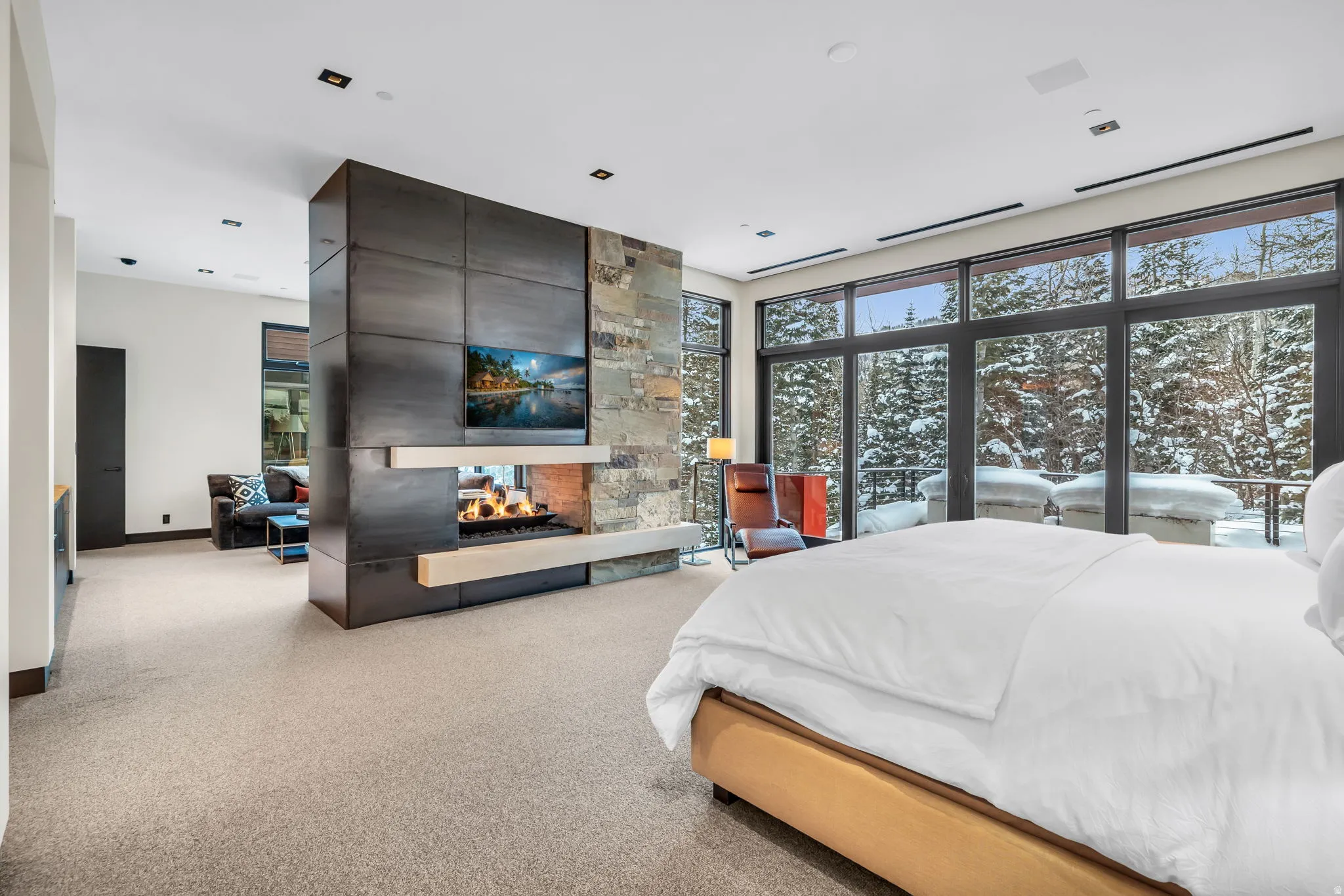 Expansive floor-to-ceiling windows overlooking a snow-covered forest