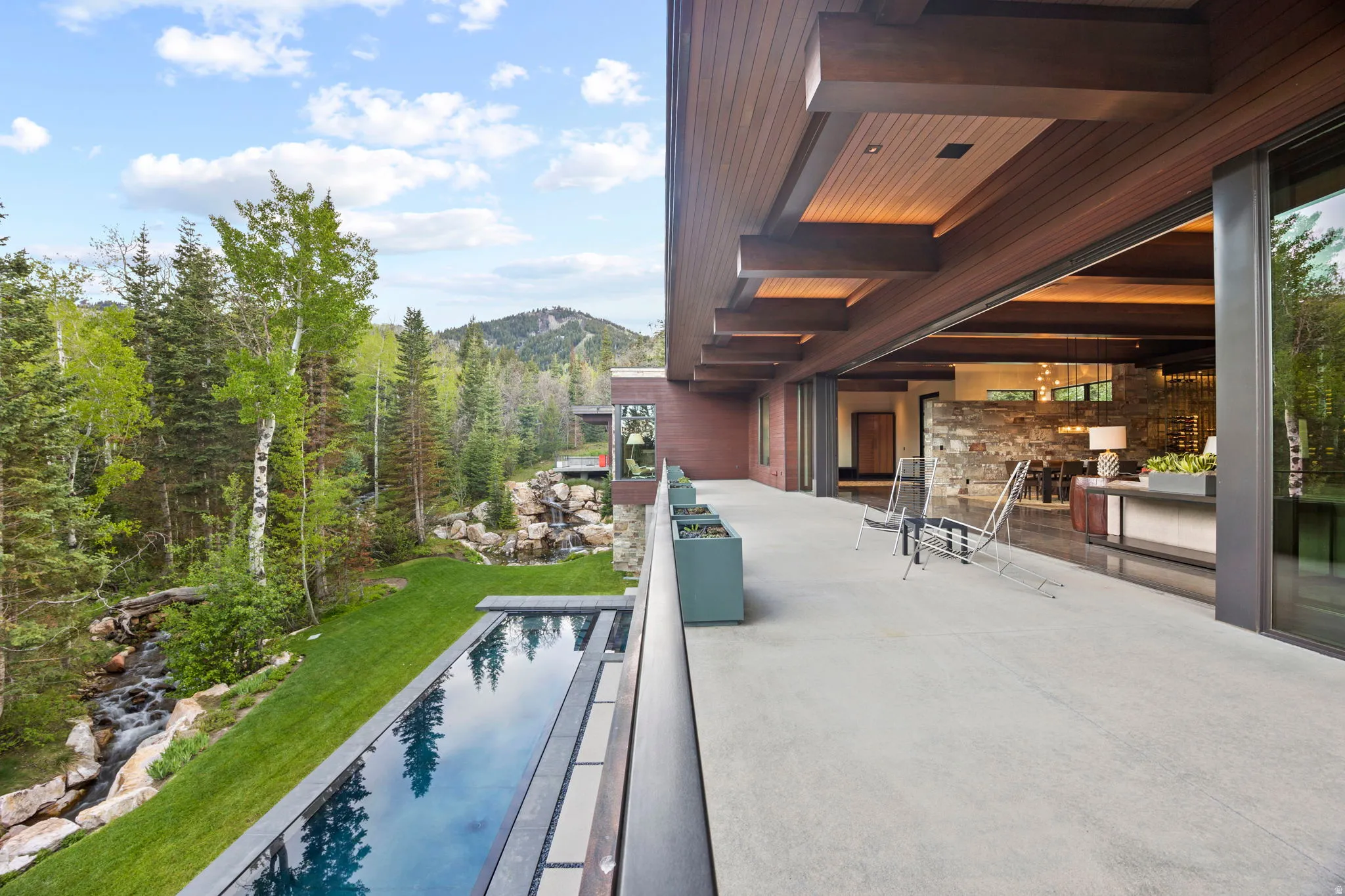 Expansive outdoor patio with an infinity-edge pool, providing direct access to the interior living space through large sliding glass doors