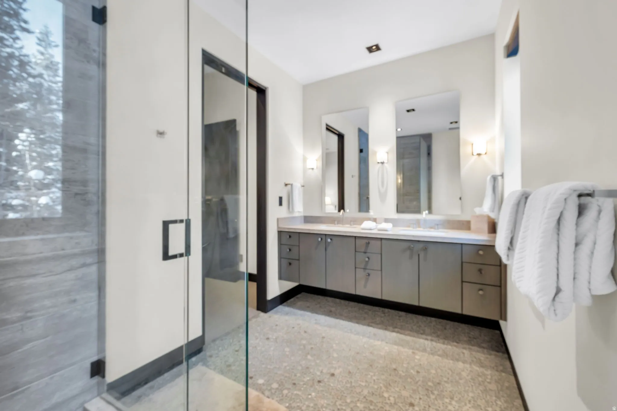 Bathroom featuring a dual vanity with light countertops, recessed sinks, and sconce lighting