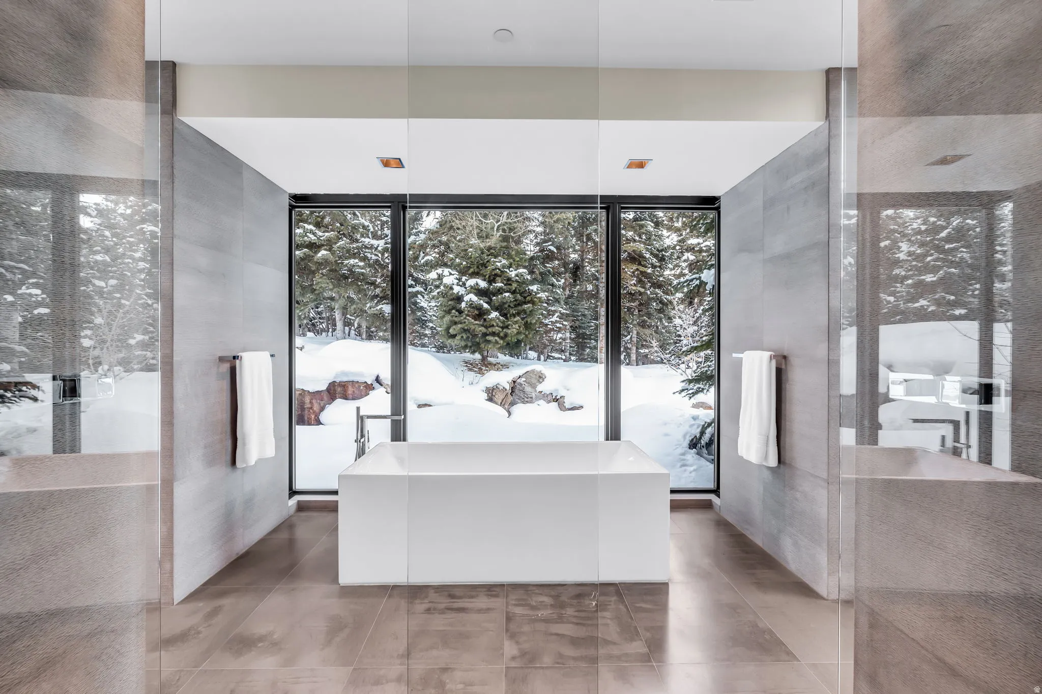 Freestanding soaking tub centered before expansive floor-to-ceiling windows