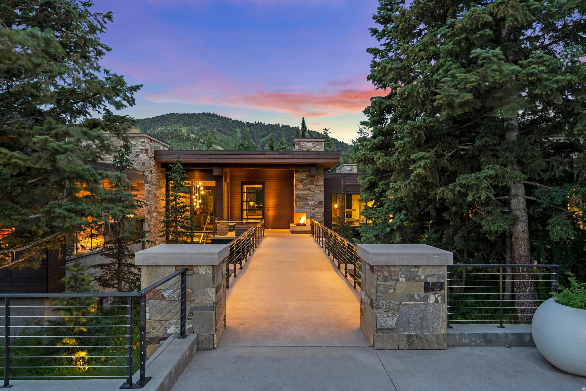 Stone and wood-clad exterior featuring a concrete entry ramp with cable railings