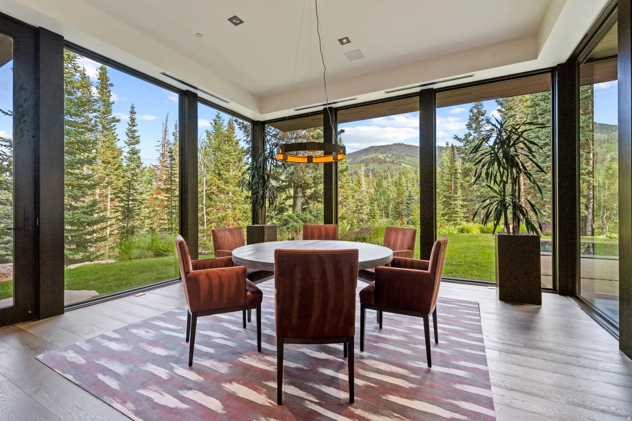 Dining area featuring a contemporary round table, wood-finish flooring, and a linear pendant light fixture