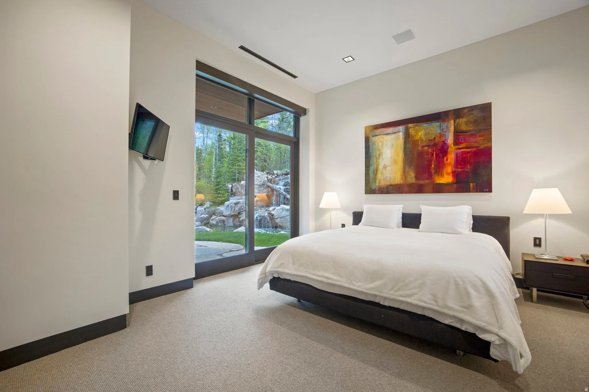 Room featuring floor-to-ceiling glass doors, recessed ceiling lighting, wall-mounted display, and light-toned carpeting