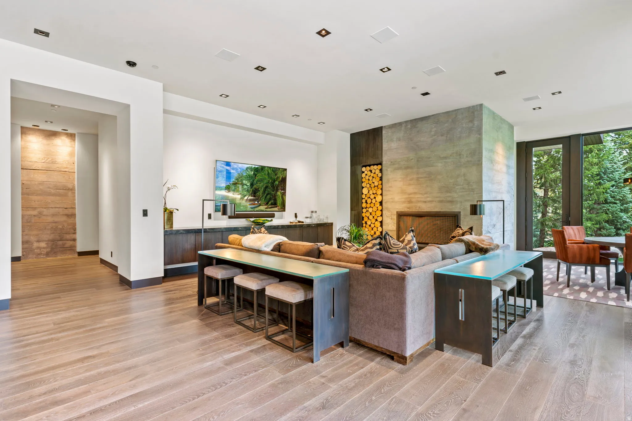 Spacious living area featuring light wood-finish flooring, a contemporary fireplace with a concrete surround, and a built-in wood storage niche