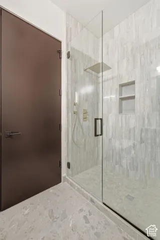 Walk-in shower with full-height tile surround, built-in shelving, glass enclosure, and a square rain shower head