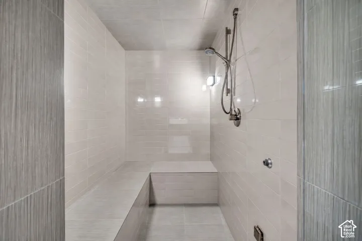 Expansive walk-in shower featuring light-toned subway tile, a built-in bench, brushed nickel shower fixtures, and integrated wall lighting