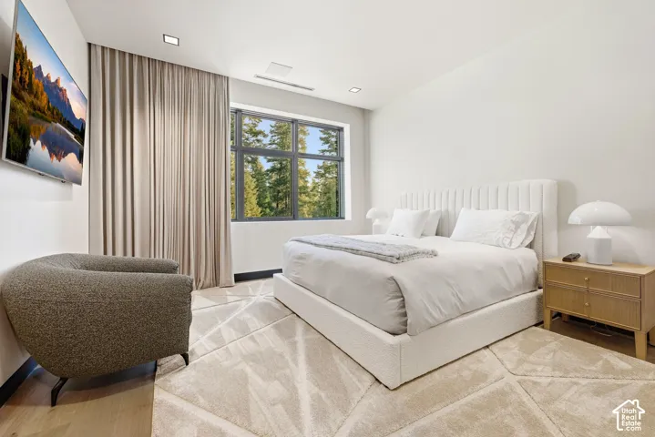Large window with exterior scenery, recessed ceiling lighting, light-toned wall-to-wall carpeting, and wood-finish flooring